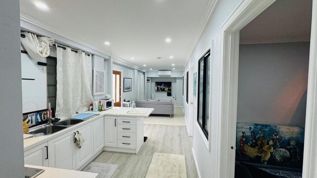 una cucina con armadi bianchi e lavandino e un soggiorno di Charming Cozy Stay In Heart Of St Albans a St Albans