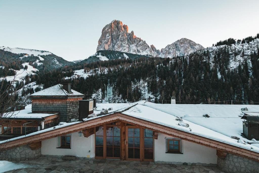 a house in the mountains with snow on the roof at Dorfhotel Beludei in Santa Cristina in Val Gardena