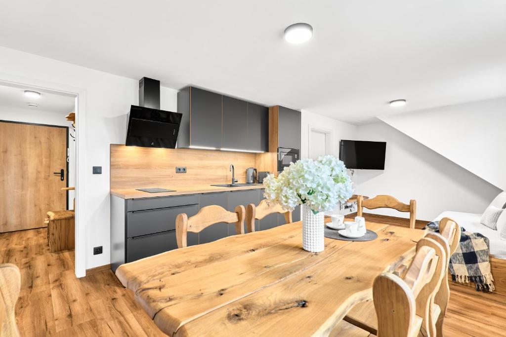 a kitchen and dining room with a wooden table and chairs at Residence Koubek - stylové apartmány s parkováním in Boží Dar