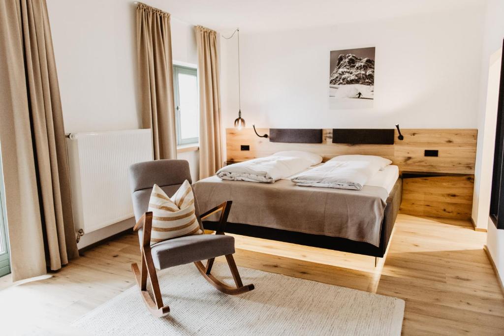 a bedroom with a bed and a chair at Hotel Hubertus in Lofer