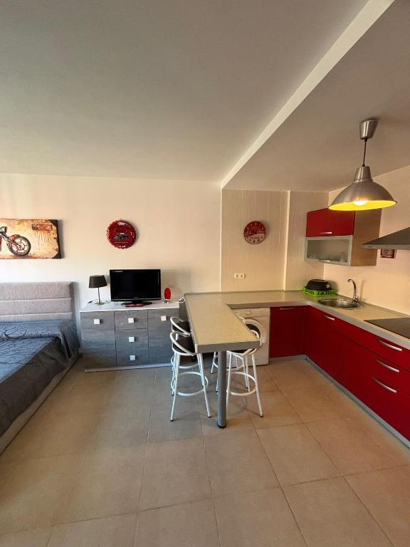 a kitchen with red cabinets and a table and chairs at El Mocan Apartment Palm Mar in Palm-mar