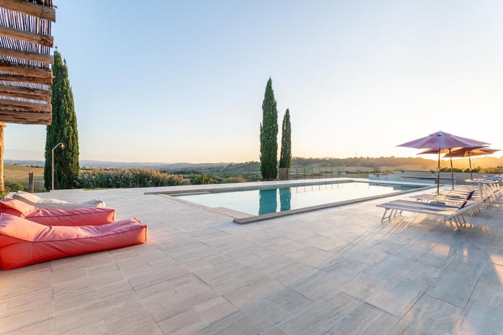 a patio with a pool and chairs and an umbrella at Pieve Vecchia - Charm and modern villa in Tuscany in Campagnatico