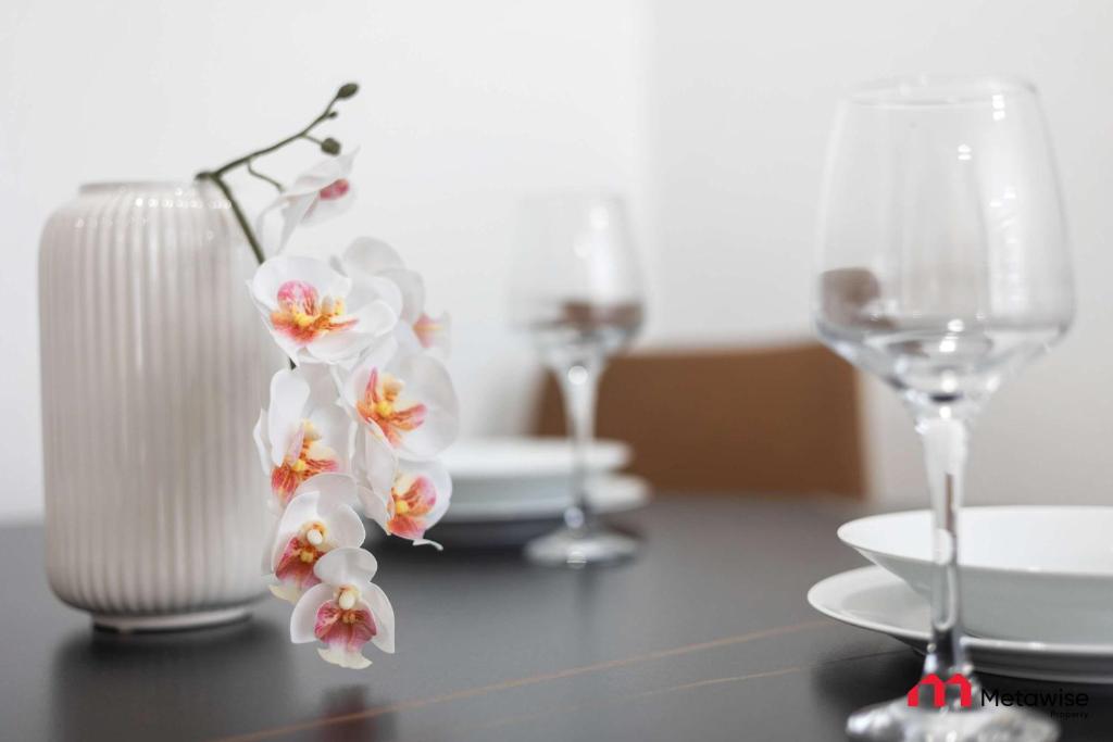 a table with glasses and a white vase with flowers at MetaWise BnB Bright 1Bed Studio Near Kings Cross in Sydney