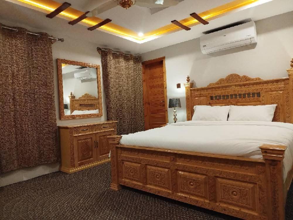 1 dormitorio con cama grande de madera y espejo en Crown Resort, en Skardu