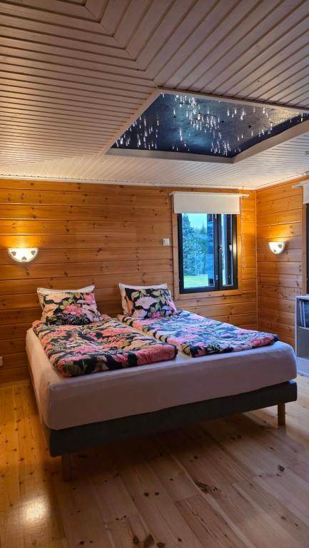 a bed in a room with a wooden wall at Lakeside Hideaway in Rovaniemi