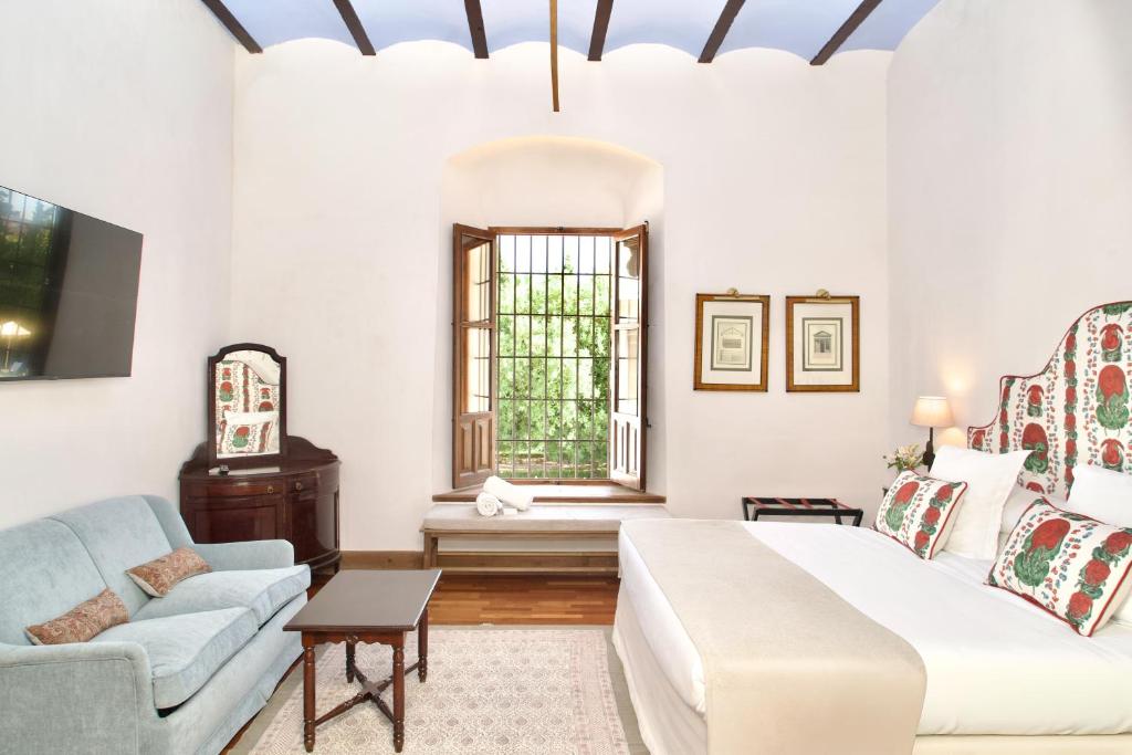 a bedroom with a bed and a couch and a window at Monasterio de San Francisco in Palma del Río