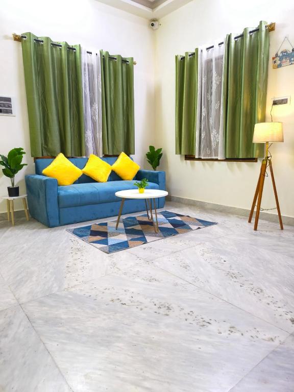 a living room with a blue couch and a table at Flickstays Elara in Bangalore