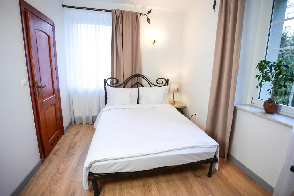 a bedroom with a bed with white sheets and a window at Villa Admiral in Gdynia
