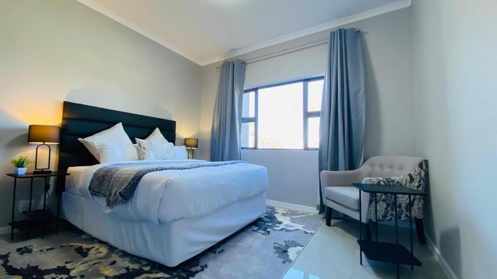 a bedroom with a bed and a chair and a window at Sun-Ash Sea Gardens in Port Shepstone