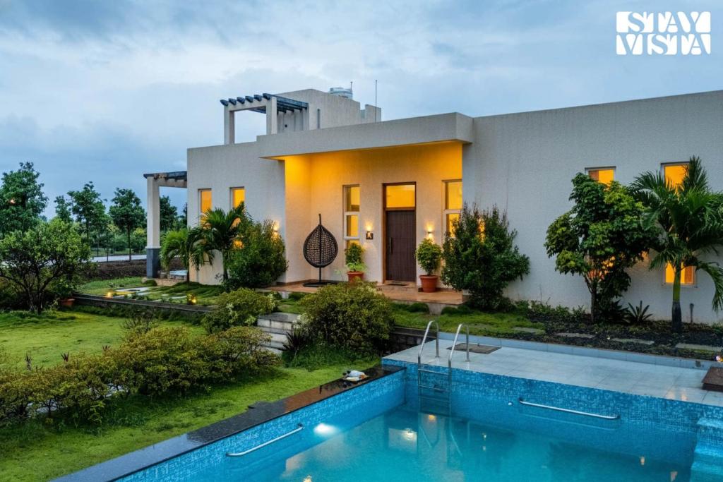 a house with a swimming pool in front of it at StayVista at Casa Shwika with Pool and Lawn in Hyderabad