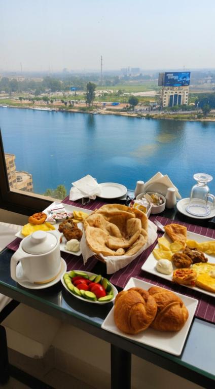 a table with food and a view of the water at Grand Bayan Hotel & Apt at Nile Plaza in Cairo