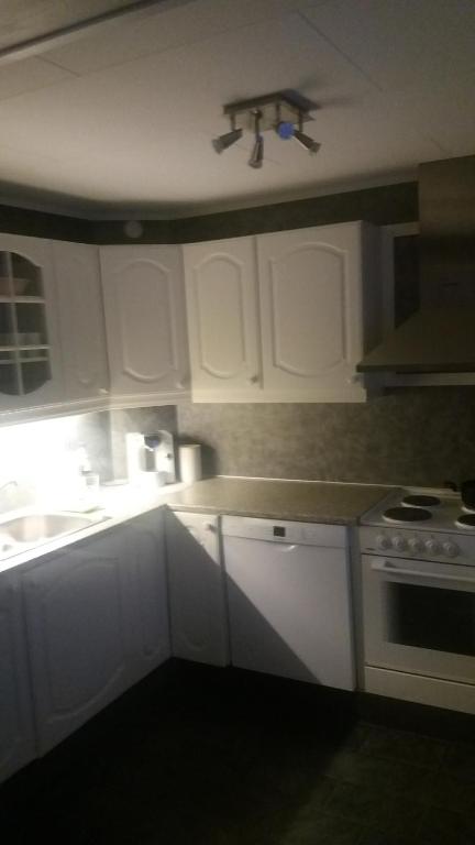 Una cocina con gabinetes blancos, un fregadero y una estufa. en Apartament 2, en Havøysund