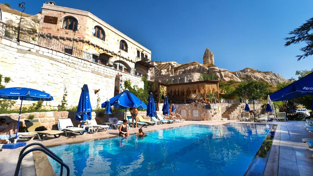 a pool with blue umbrellas and people sitting in it at Grand Elite Cave Suites in Goreme