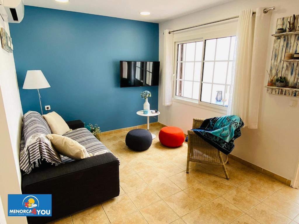 een woonkamer met een zwarte bank en een blauwe muur bij Appartamento Safir Son Bou con vista mare e piscina in Son Bou