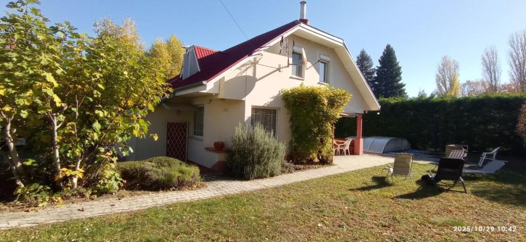 een klein wit huis met een grasveld bij Magyar Tenger Pihenőház, 4-8 főre Balatonakarattya in Balatonakarattya