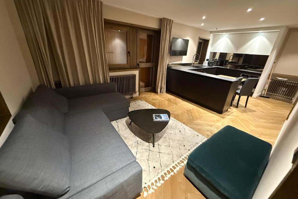 Una sala de estar con un sofá y una cocina. en La Forêt 15, en Méribel