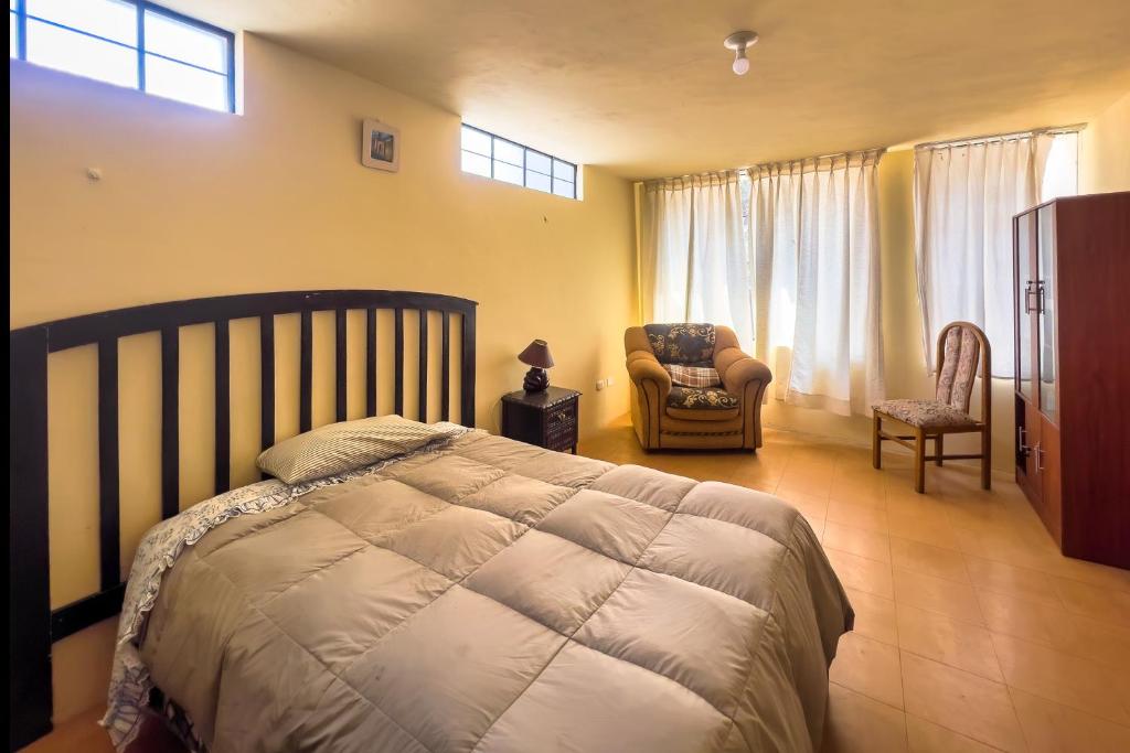 a bedroom with a bed and a chair and window at Namaste Bnb in Yanahuara