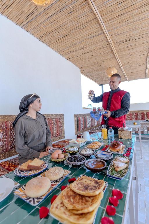 a man and a woman standing at a table with food at Riad Al Mozyane in Fez