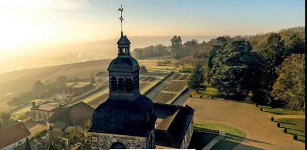 un edificio con una torre con una cruz en la parte superior en Le Clos Haton - HAUTVILLERS, en Hautvillers