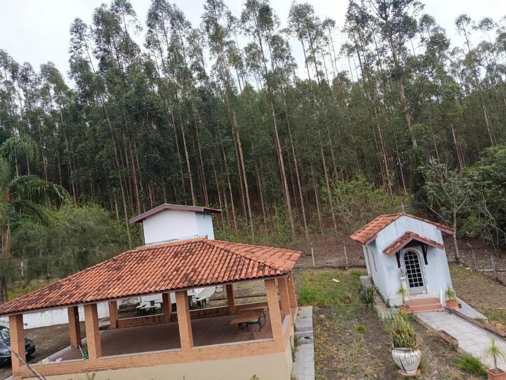 a small building with a roof with a forest in the background at Sitio Pé da Serra São Pedro in São Pedro