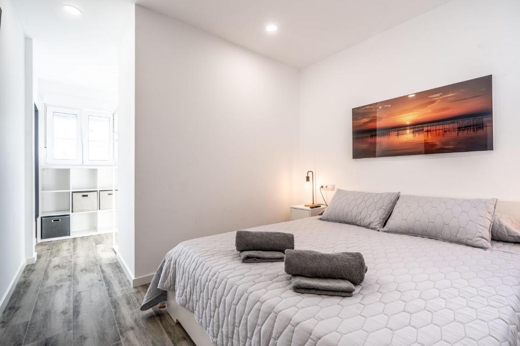 a white bedroom with a bed with two pillows on it at Duplex-Port-Valencia in Valencia
