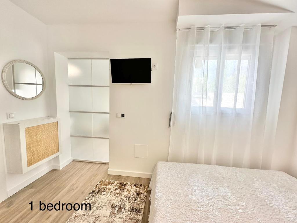 a white bedroom with a bed and a mirror at Boutique Higueron Spa in Fuengirola