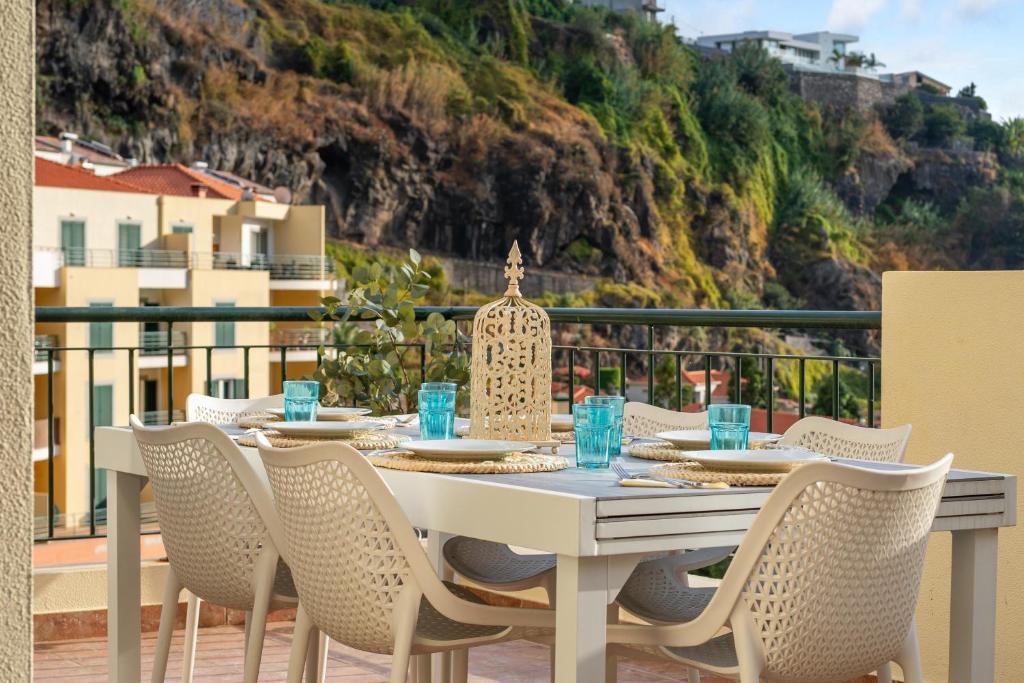 a white table and chairs on a balcony with a view at Sunny Ponta "Nomads' village" in Ponta do Sol