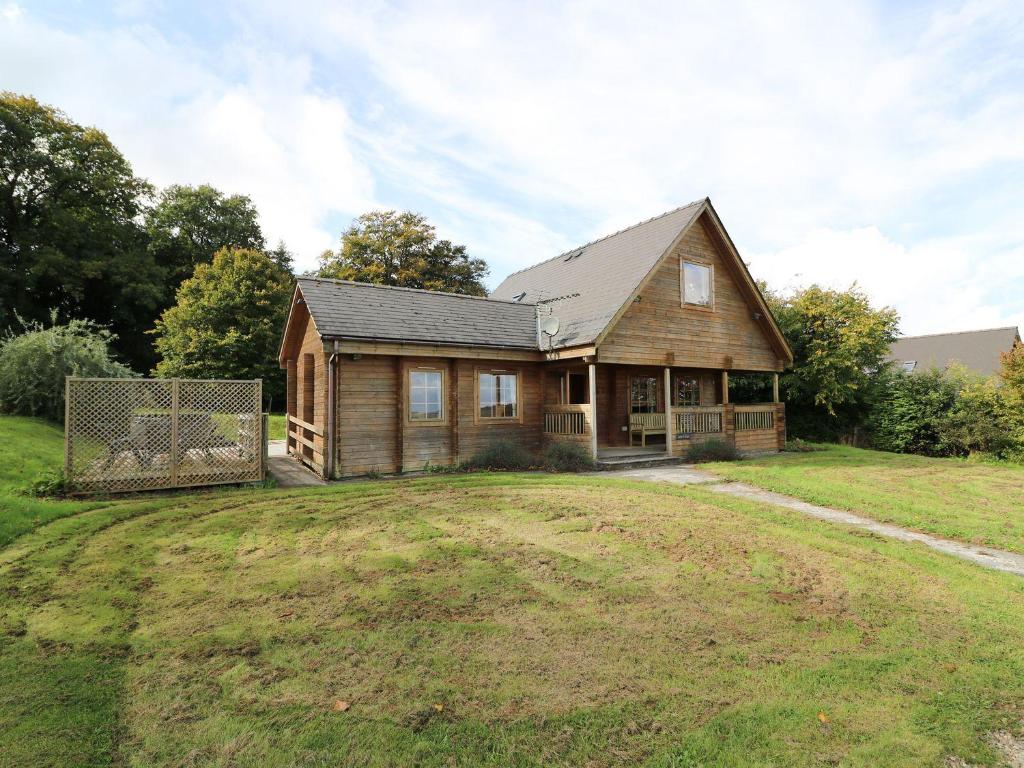 a wooden house on a field with a yard at Dan Y Coed in Discoed
