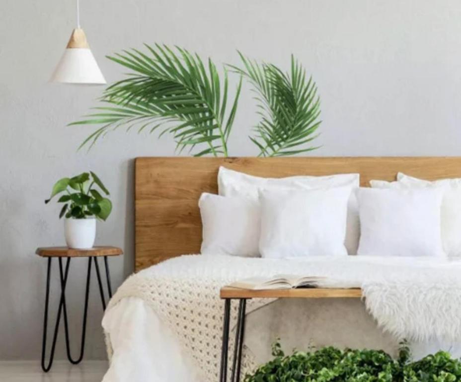 a bedroom with a bed with white pillows and plants at Soulful healing academy in Point Cook