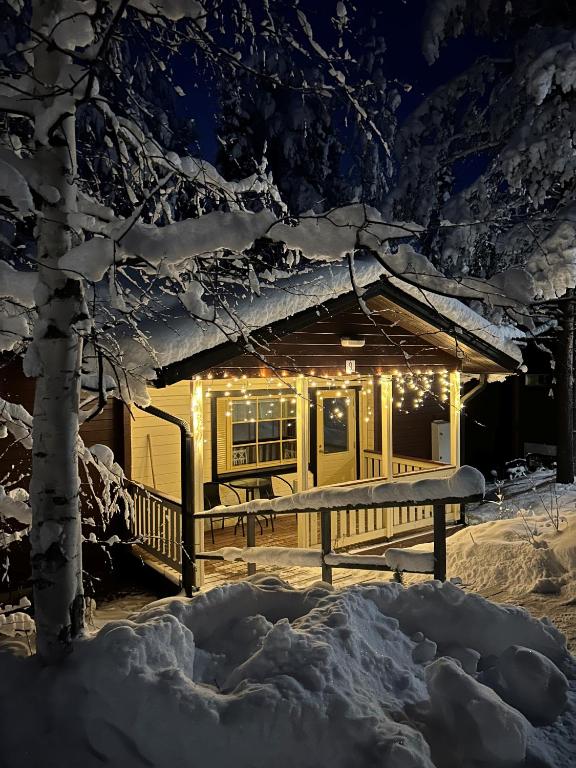 a cabin covered in snow at night with lights at Immelmökit in Levi