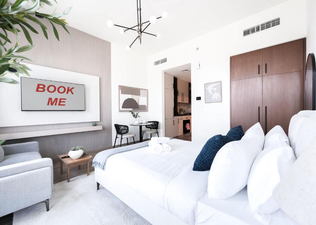 a bedroom with a white bed and a chair at StayShort - Town Square sleeps 2 in Great Location in ‘Ūd al Bayḑāʼ