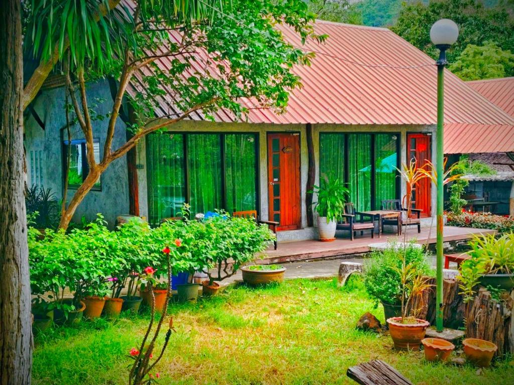 a house with a lot of plants in a yard at Phakphing Erawan Homestay - พักพิง เอราวัณ โฮมสเตย์ in Tha Kradan