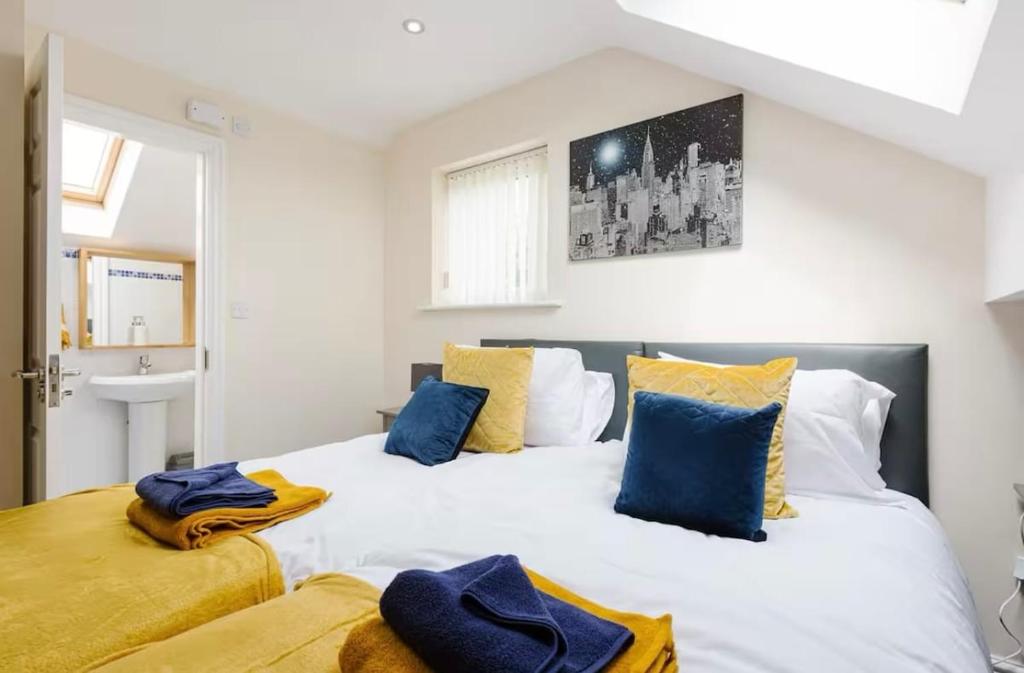 a bedroom with two beds with blue and yellow pillows at Oxheys Stays - Sleeps 7 - Home from Home in Preston