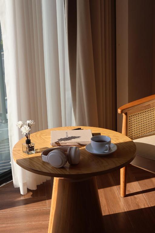 a wooden table with a plate and cups on it at Mê Stay Cat Ba in Cat Ba