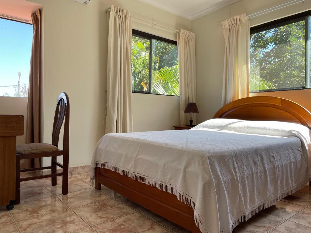ein Schlafzimmer mit einem Bett und einem Stuhl und Fenstern in der Unterkunft Habitación Cómoda y Confortable, Zona Norte, Santa Cruz in Santa Cruz de la Sierra