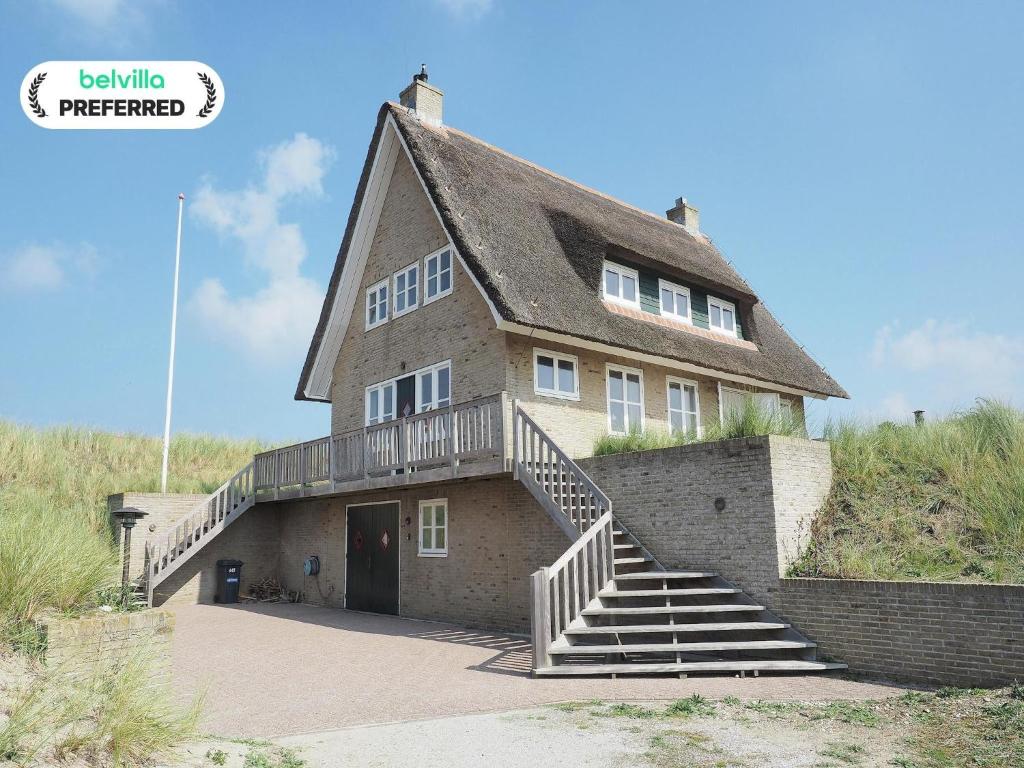 una casa grande con una escalera delante de ella en Villa in Midsland near the Sea, en Midsland aan Zee