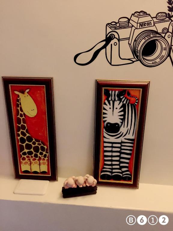 two pictures of a giraffe and a camera on a shelf at Fish House Hostel in Wujie