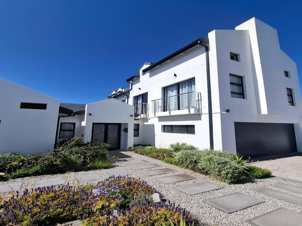 a white building with a gate and a driveway at 6 on Third in Stompneusbaai
