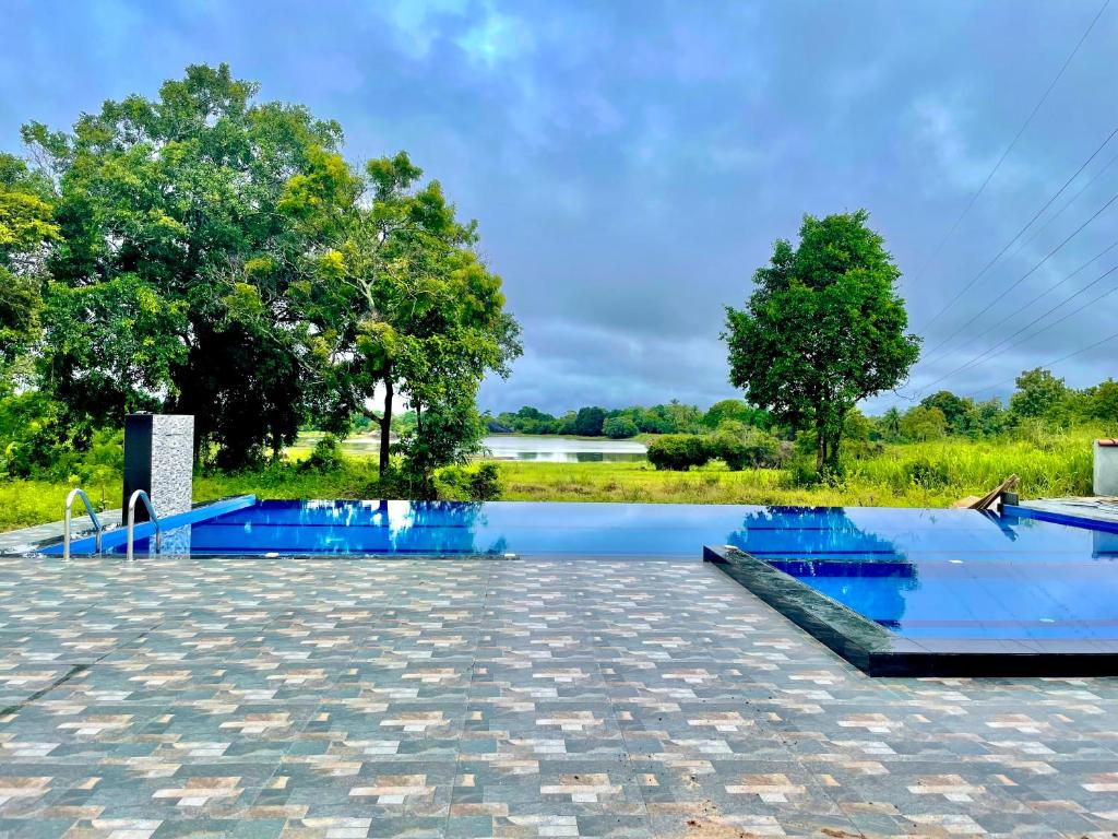 a swimming pool with blue water and trees in the background at Wooden Cabana Sigiriya in Sigiriya