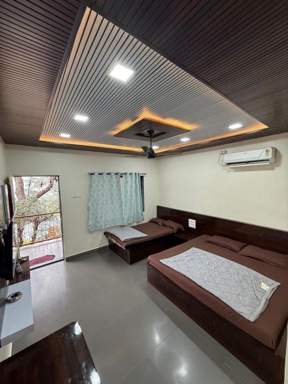 a bedroom with two beds in a room with a ceiling at Patil residency in Matheran