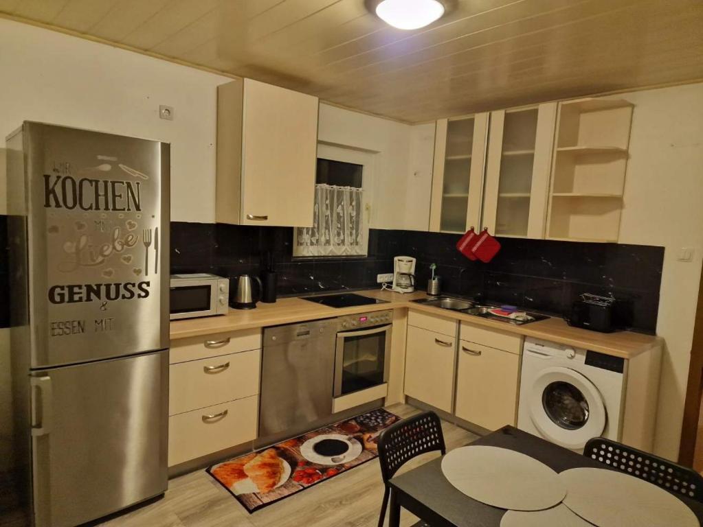 une cuisine avec un réfrigérateur en acier inoxydable et une table dans l'établissement 2-Zimmer Apartment in Gummersbach, à Fenke