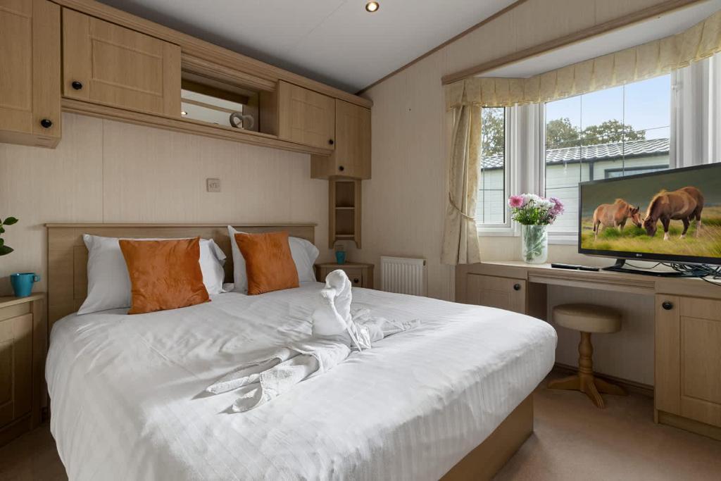a bedroom with a large white bed with a television at Greendale Splash Escape - No Commercial Sign written Vehicles,Fishing Nearby & Communal Swimming Pool Open April to September in Tedburn Saint Mary
