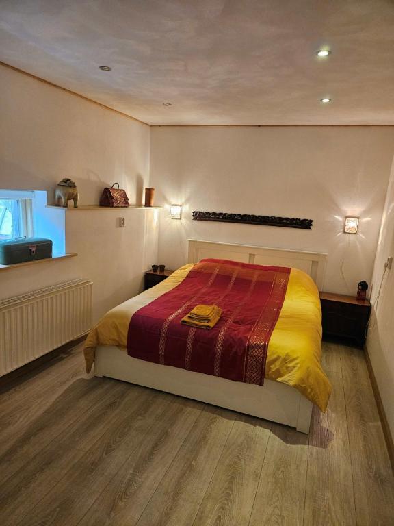 een slaapkamer met een bed met een rode en gele deken bij Hoeve de Haan in Bellingwolde