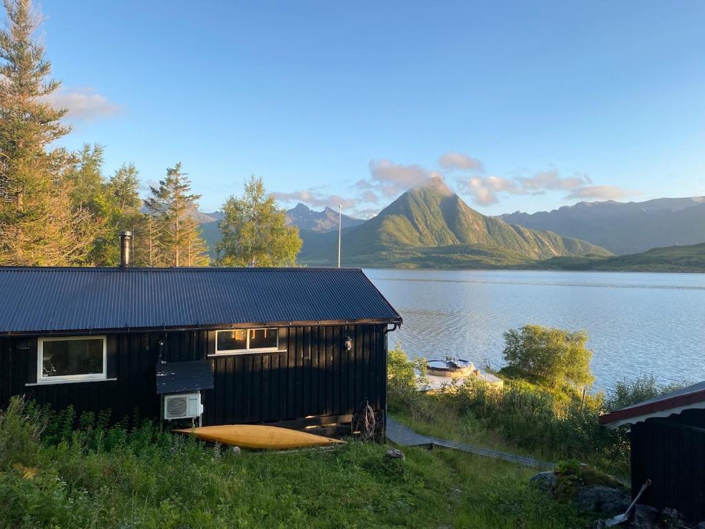 a house with a boat next to a lake at Charming cabin by the sea in Lofoten in Sandsletta