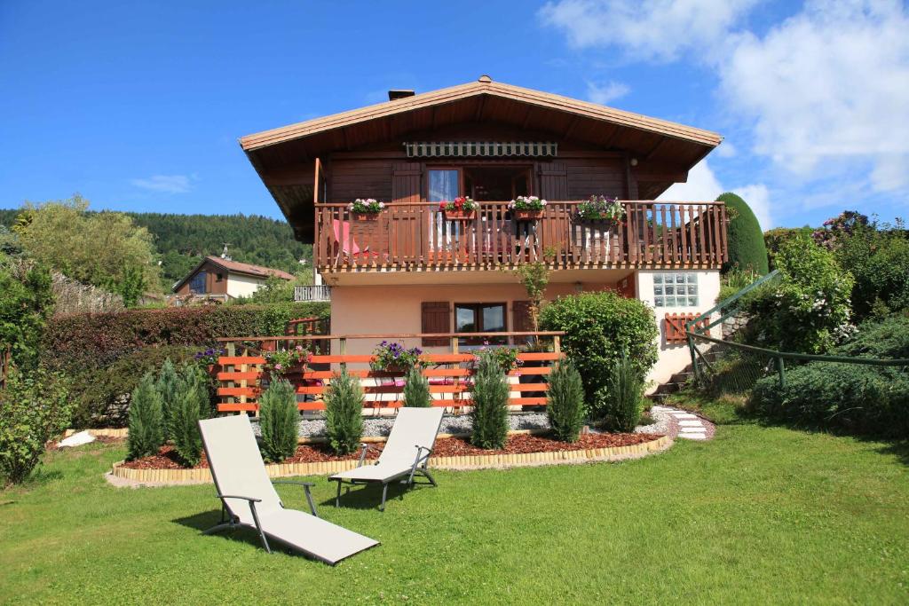 une maison avec un balcon et deux chaises dans la cour dans l'établissement Chalet exposition sud le Nid Douillet, à Gérardmer