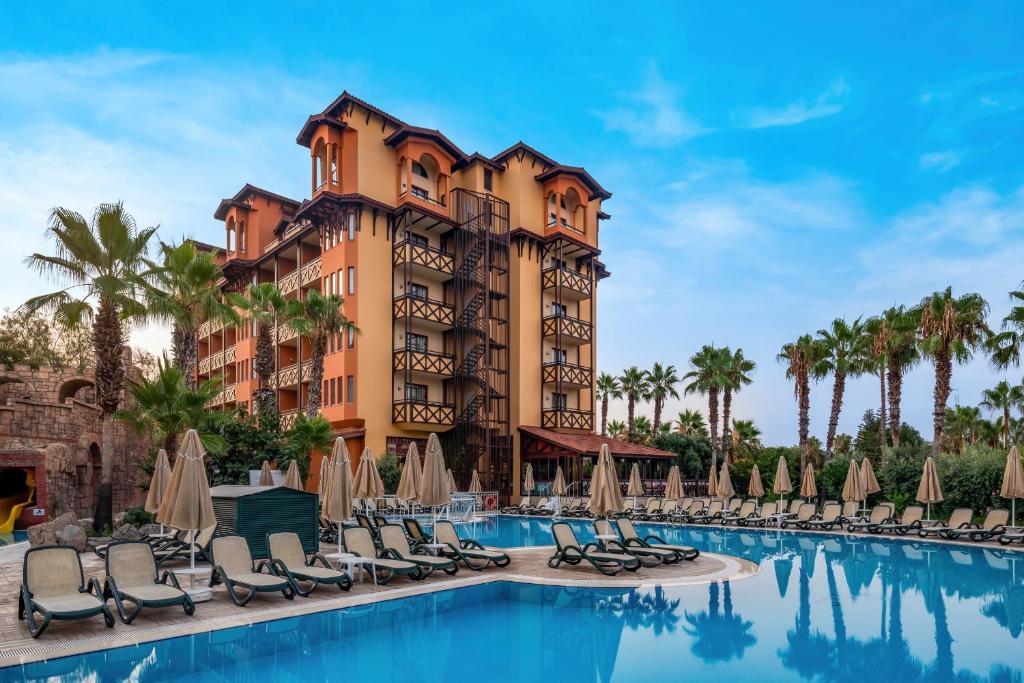 a resort with a pool and chairs and palm trees at Villa Side Hotel in Side