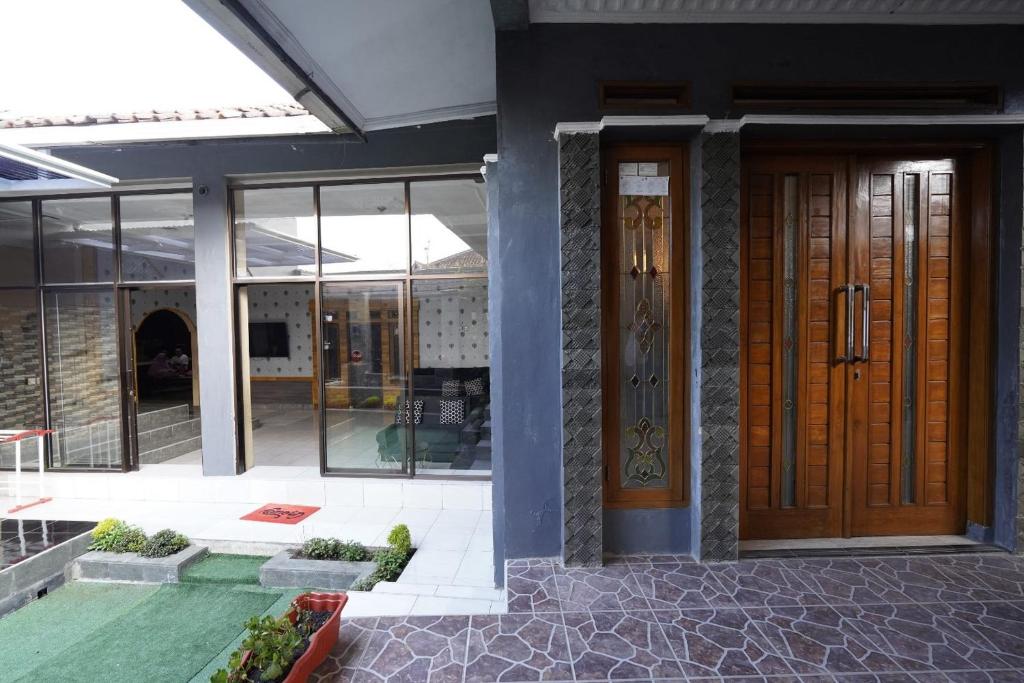 a building with a wooden door and windows at Hotel O 94911 Syariah Anggrek Guest House in Lebakwangi