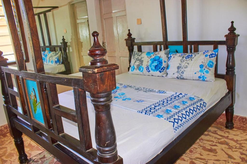 a wooden bed with blue and white pillows on it at MK Casa Modern 3BR Retreat Fully Furnished in Malindi