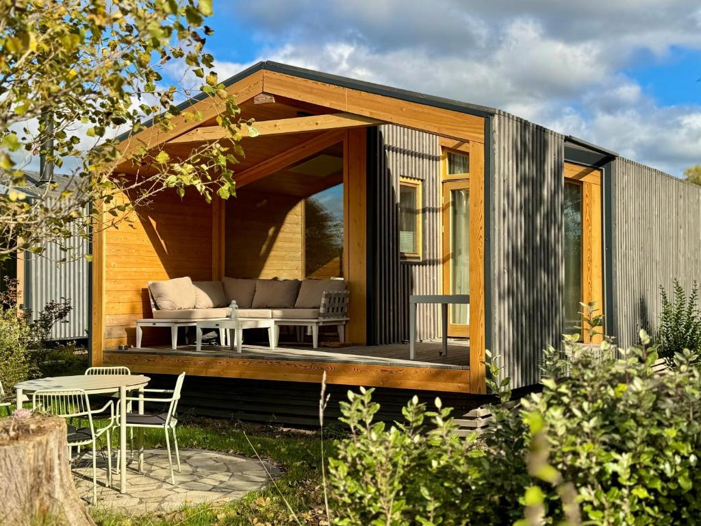 ein kleines Haus mit einer Terrasse und einem Tisch in der Unterkunft Tiny House im Grünen 101 - Terrasse, WLAN, Wiesenblick in Barförde