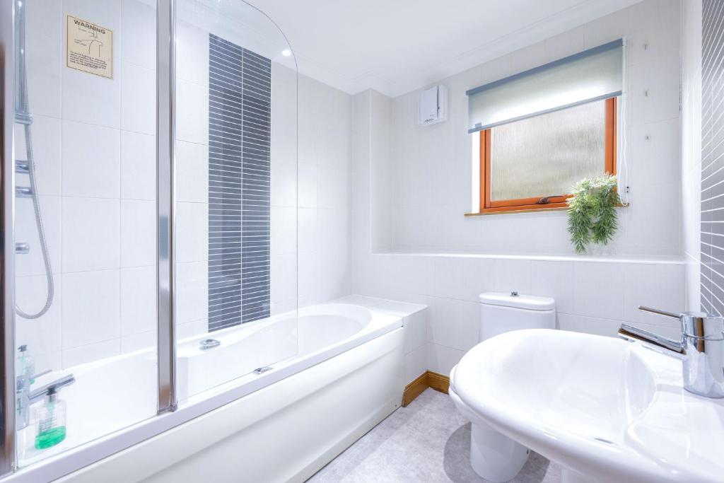 フォレスにあるForres Nightsの浴槽と洗面台のある白いバスルーム